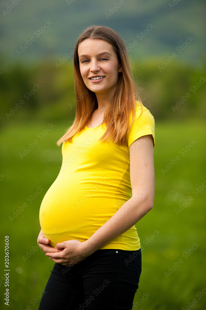 gnant woman in yellow t shirt on a green meadow in spring gnant woman in yellow t shirt on a green meadow in spring