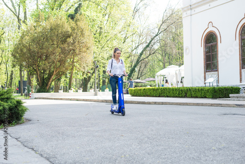 Woman using electric scooter in the park on a sunny day