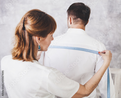 фотографія Woman tailor takes measures with male models