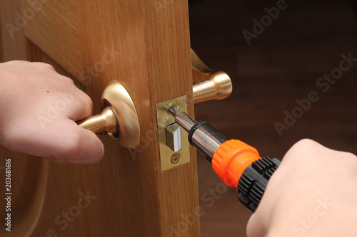 man with a screwdriver in his hand repairs the inner door. door lock