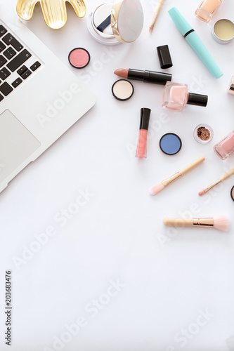 Flat lay composition with makeup products for woman and laptop on white background