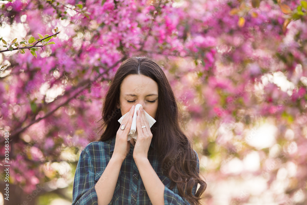 Woman blowing nose because of spring pollen allergy - obrazy, fototapety, plakaty 