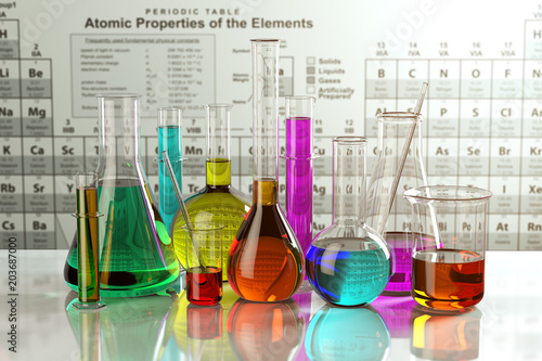 Photo Test glass flasks and tubes with colored solutions on the periodic table of elements