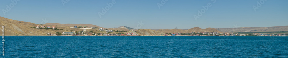 Panorama of the sea coast against a blue sky. Shooting taken from the water side