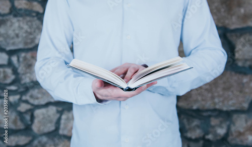 Young man opening and reading a book.