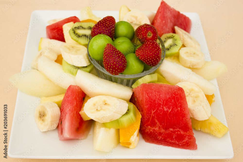 Fruits on a plate. Green plum, strawberry, banana, kiwi, watermelon, orange and apple. Fruits on a plate. Green plum, strawberry, banana, kiwi, watermelon, orange and apple.