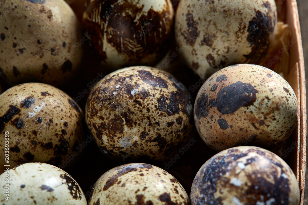 Obraz premium Quail eggs in a box on a vintage wooden background, top view, selective focus.
