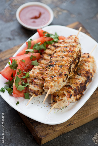 Close-up of lula kebabs made of chicken meat and served with vegetables, studio shot, selective focus