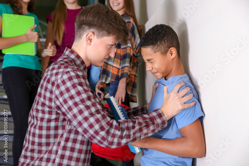 Teenager bullying African American boy indoors