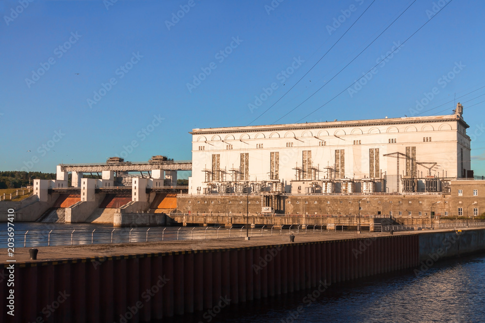 River dam for fuel and power generation of the hydroelectric power station on the blue sky background summer sunny day.