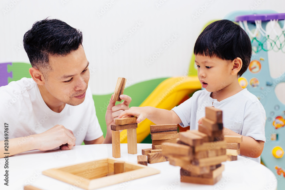 Asian child and father playing with wooden blocks in the room at home. A kind of educational toys for preschool and kindergarten kids Asian child and father playing with wooden blocks in the room at home. A kind of educational toys for preschool and kindergarten kids