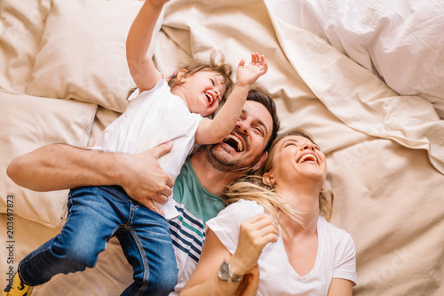 Happy family having fun in the bedroom while they lie on bed photo