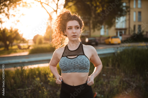 Young fit woman in sportswear is getting ready to start running outdoors