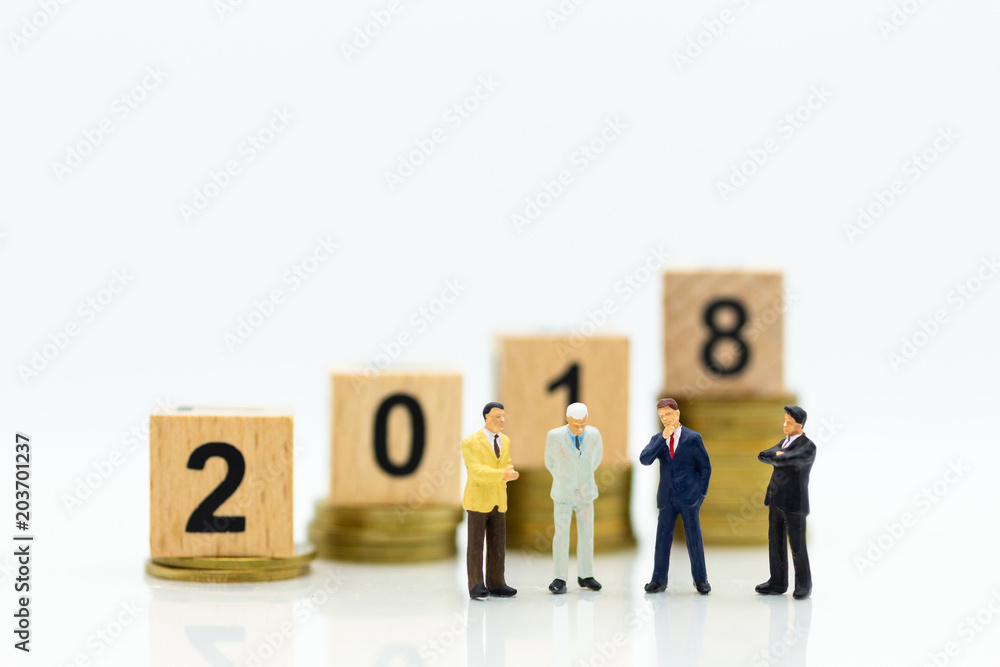 Miniature people: Businessman standing with stack of coins and wooden block 2018. Image use for investment for benefit of year, business concept.