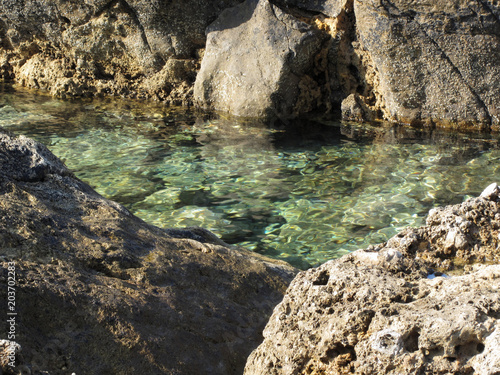Crystal clear sea water between rocks . Tuscany, Italy