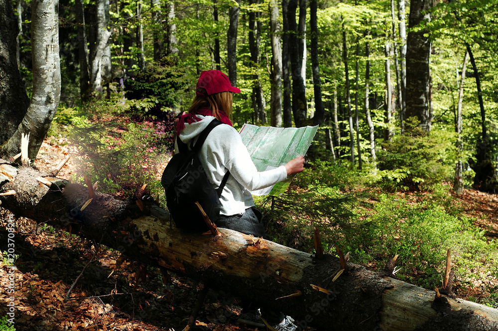 young girl with a backpack in the forest watching map, travel concept in the wild, copy space, close-up young girl with a backpack in the forest watching map, travel concept in the wild, copy space, close-up