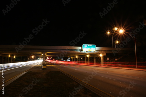 Traffic Traveling East and West along Sample Road in Pompano Beach at Night under the I-95 Overpass with North to West Palm Beach Sign