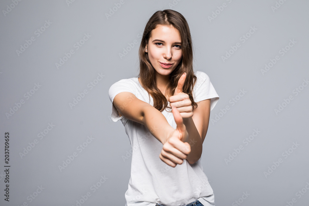 Young happy cheerful woman showing thumb up isolated gray background
