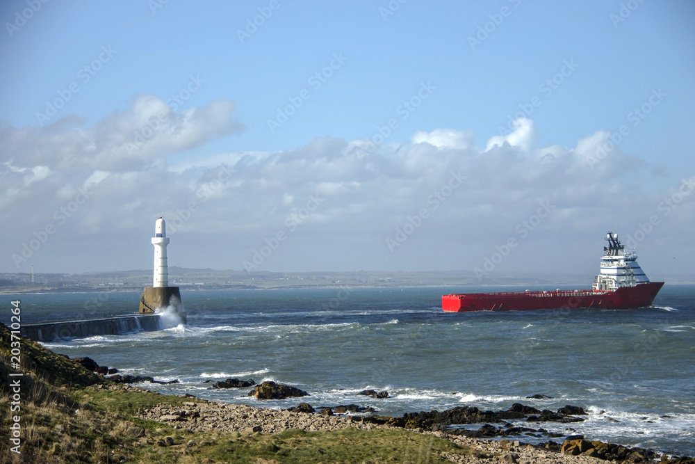 Ship passes lighthouse in Aberdeen, Scotland, United Kingdom