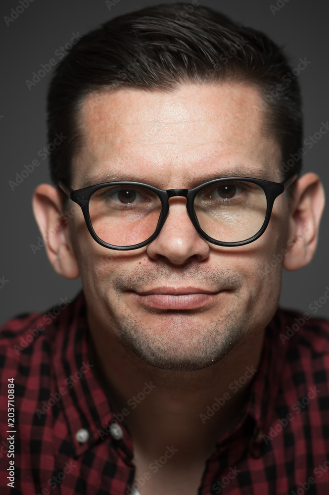 Portrait of cute young hipster man in plaid shirt and glasses showing various emotions on gray background Portrait of cute young hipster man in plaid shirt and glasses showing various emotions on gray background