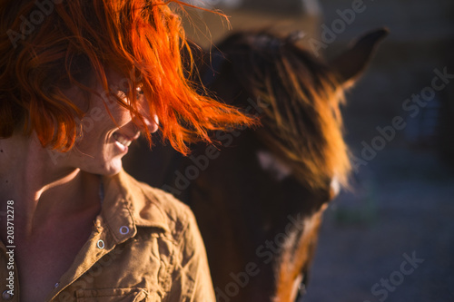 red hair beautiful young woman lifestyle with best friend horse in countryside. portrait of paople and animals for pet life concept outdoor under the sun photo