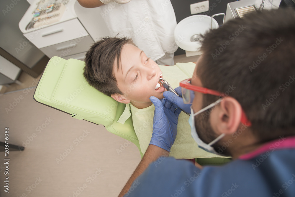 Teenager having his tooth removed at the dentist office - oral hygiene health care concept Teenager having his tooth removed at the dentist office - oral hygiene health care concept