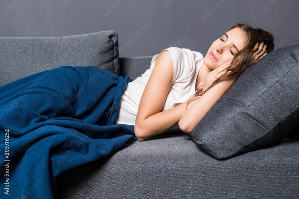 Beautiful young woman is sleeping and seeing sweet dreams om sofa at home.