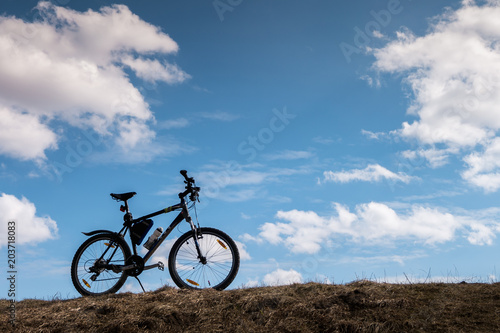 Fototapeta Naklejka Na Ścianę i Meble -  Bike silhouette in blue sky with clouds. symbol of independence and freedom