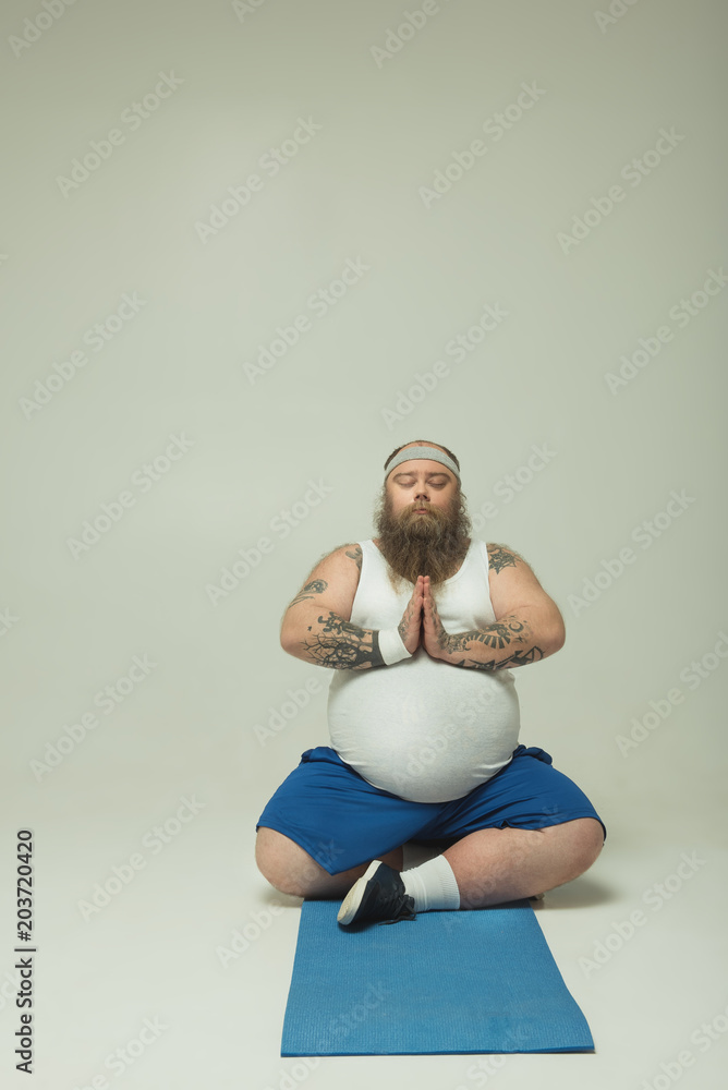 Fototapeta Man doing yoga pose on a mat