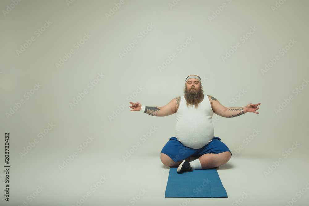 Man meditating on a yoga mat - obrazy, fototapety, plakaty 