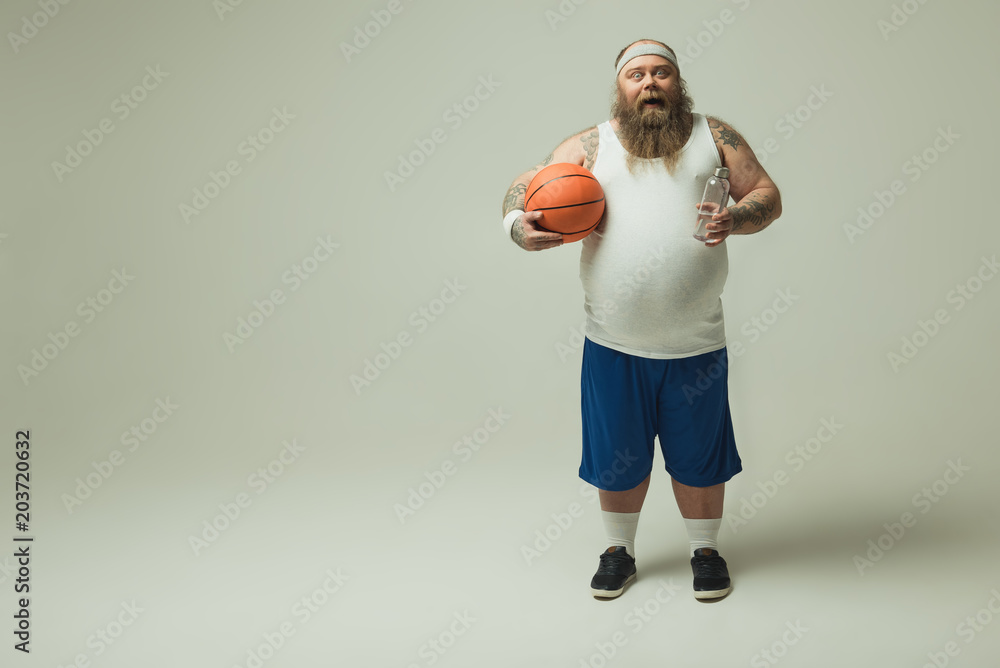 Man holding a bottle of water and a basketball