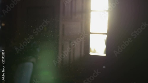 Dust floating in the air of a dark room with an open window and sunglare