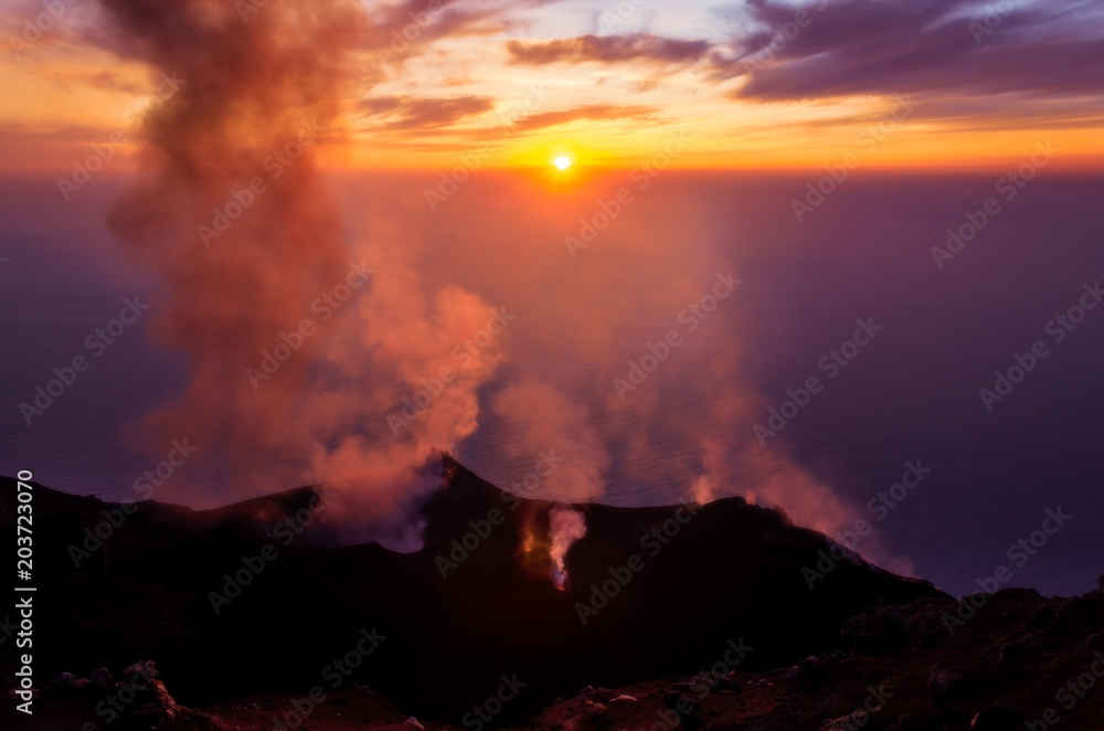 Smoking erupting volcano on Stromboli island at colorful sunset, Sicily
