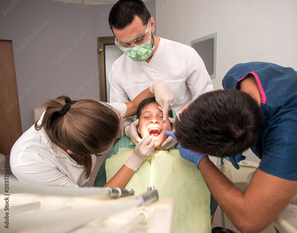 Obraz premium Boy with perfect teeth at the dentist doing check up with the clinic at the background - oral hygiene health care concept