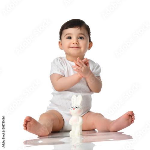 9 month infant child baby girl toddler sitting in white shirt with bunny toy isolated on a white 