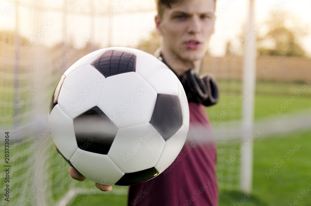 Closeup Teen holding soccer ball in the goal, selective focus on ball 
