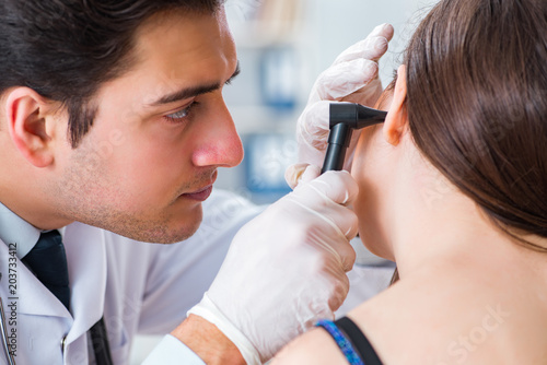 Doctor checking patients ear during medical examination photo