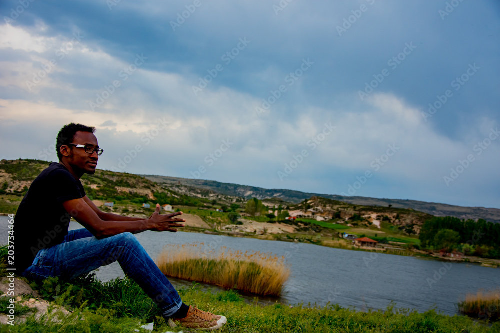 Young black man posing on the lake coast