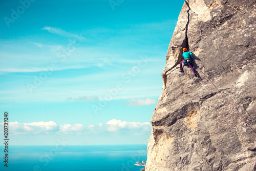 Girl in helmet climbs the rock.