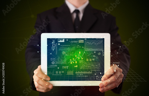 Businessman holding tablet with strategy and business related graphics