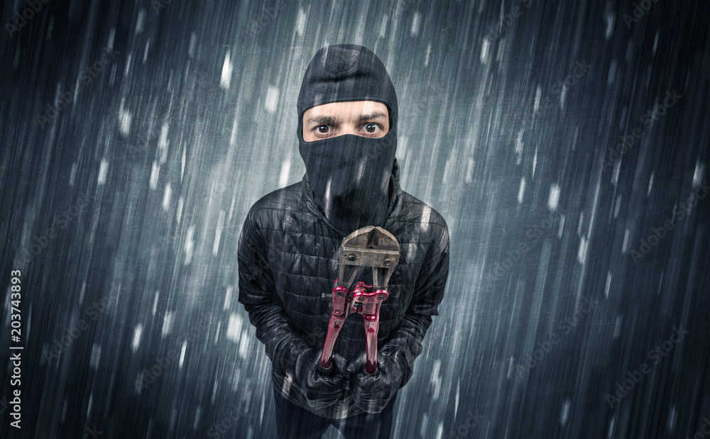 Burglar in action in black clothes with rainy concept. 