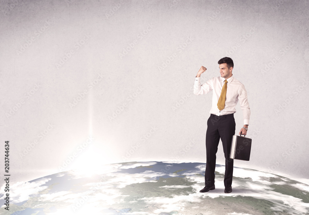 A young elegant office worker standing on top of a drawn world globe while celebrating his successful career concept. A young elegant office worker standing on top of a drawn world globe while celebrating his successful career concept.