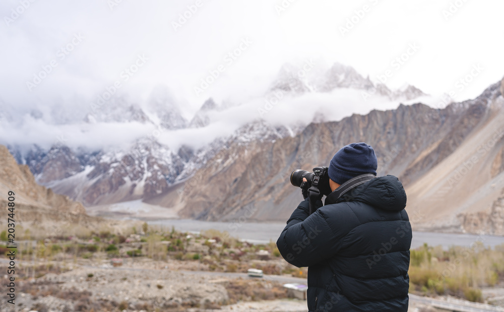 Photographer taking photograph of mountain landscape by dslr camera