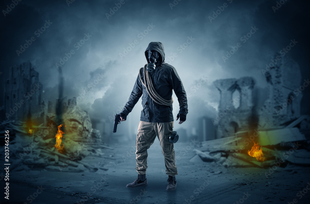 Fototapeta premium Destroyed place after a catastrophe with man in gas mask and weapon on his hand 
