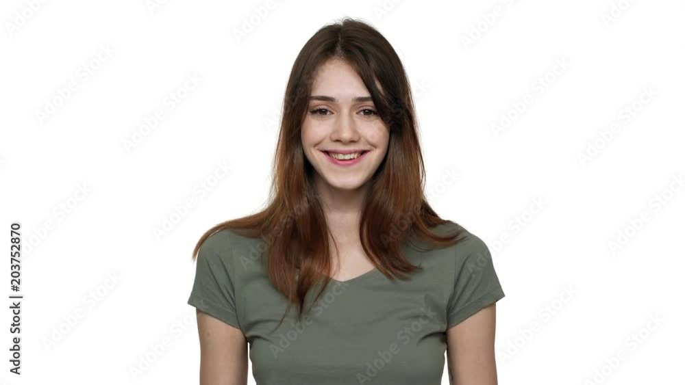 Portrait of seductive woman 20s wearing basic t-shirt touching her beautiful brown hair and smiling, isolated over white background in studio. Concept of emotions Portrait of seductive woman 20s wearing basic t-shirt touching her beautiful brown hair and smiling, isolated over white background in studio. Concept of emotions