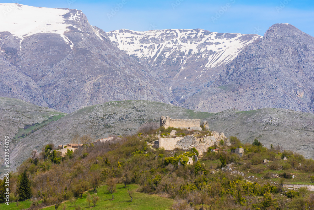 Alba Fucens (Italy) - An evocative Roman archaeological site with amphitheater and ruins of medieval castle, in a public park in front of Monte Velino mountain with snow, Abruzzo region, central Italy
