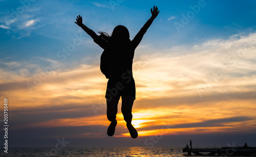 The girl jumping silhouette at the sea with sunset sky.