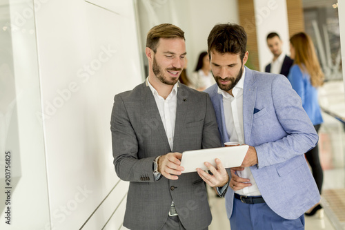 Two young businessmen with digital tablet in office
