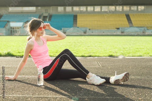 Beautiful girl resting after workout at stadium