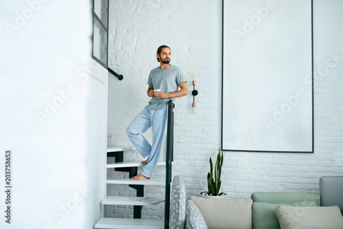 Young Man With Cup Of Coffee At Home In Morning